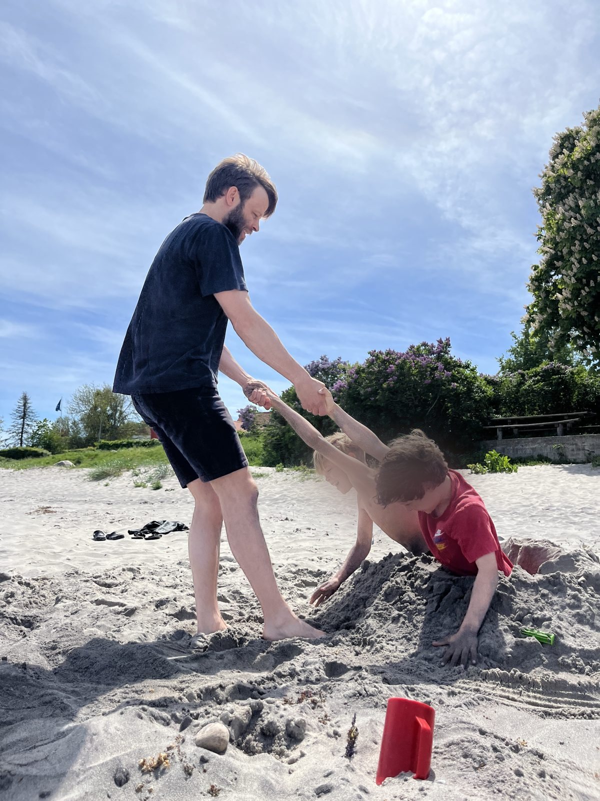 Far leger med sine børn på stranden — om at blive vred på sine børn